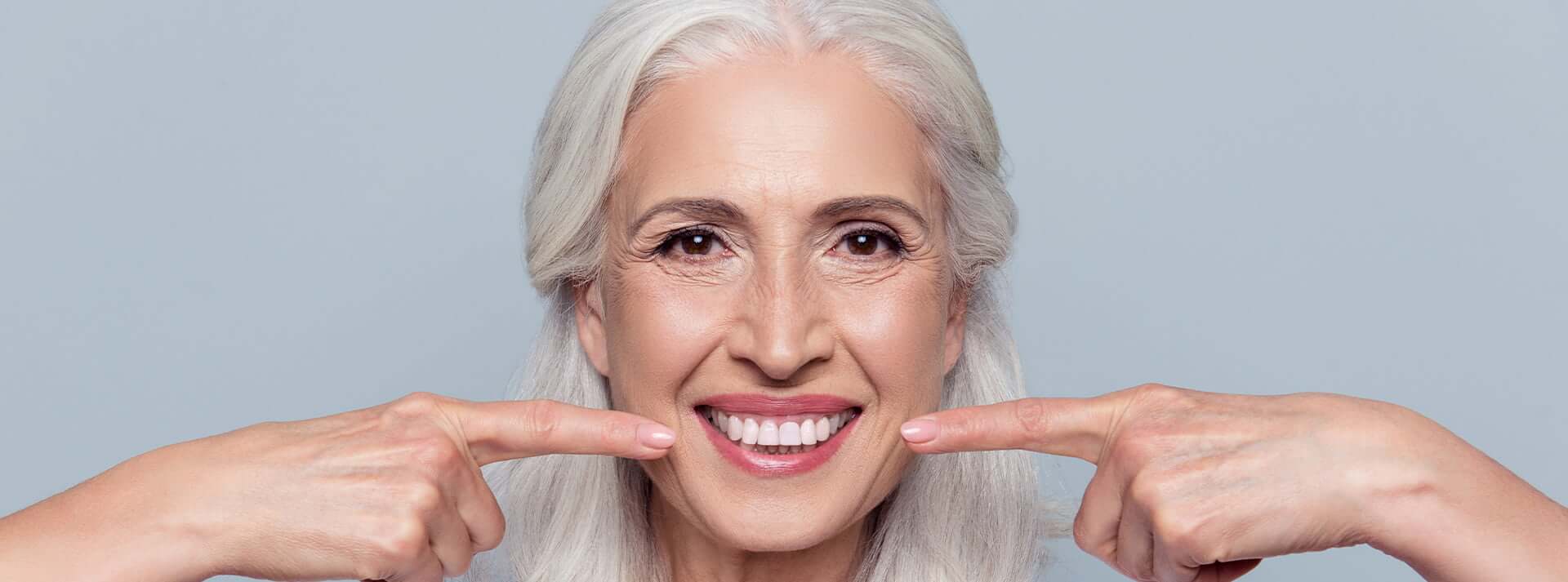 Older woman pointing to bright smile